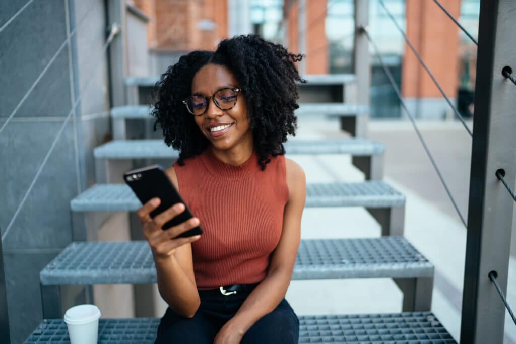 Woman sitting on a set of stairs looking at her phone