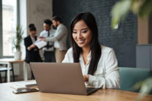 young asian woman smiling at laptop